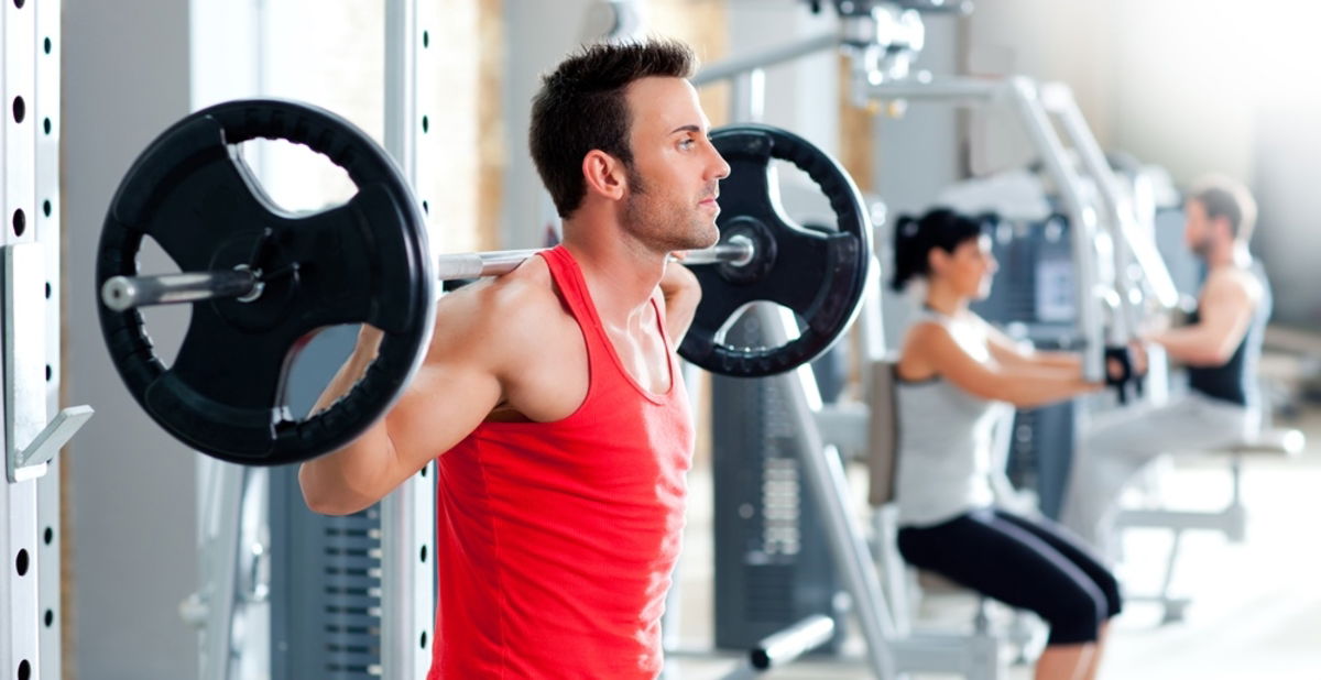 Hombre haciendo sentadillas con barra cargada