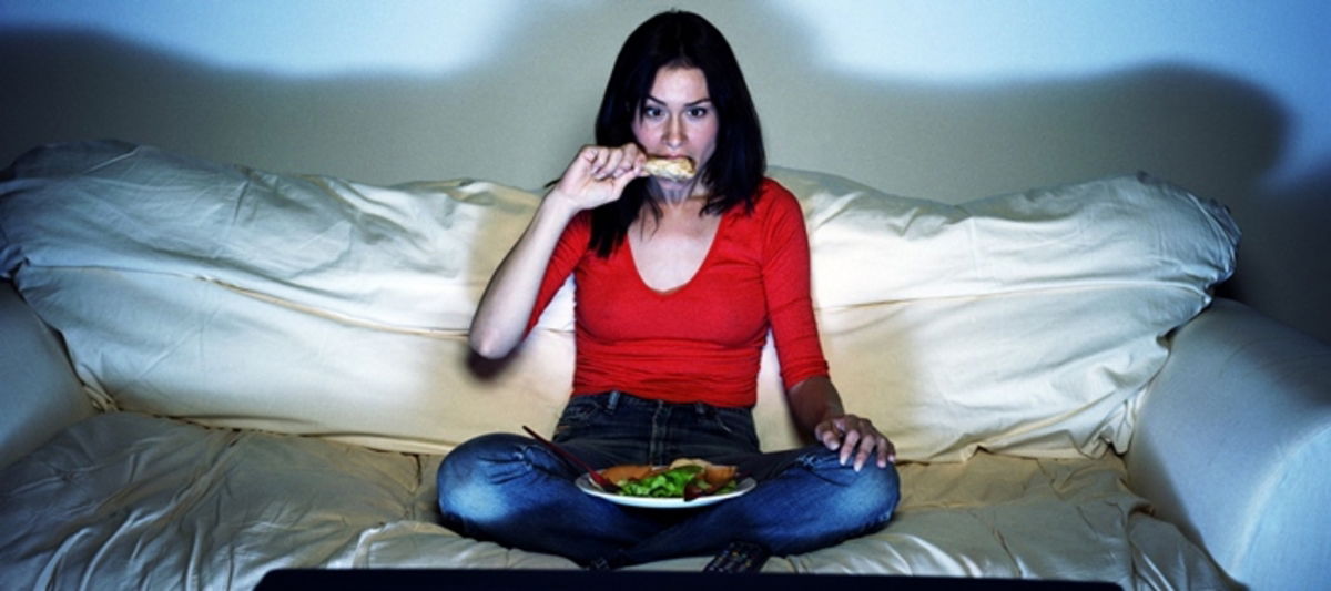 Chica cenando frente a TV