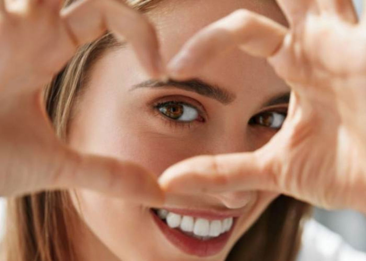 Mujer formando corazon  cerca del ojo