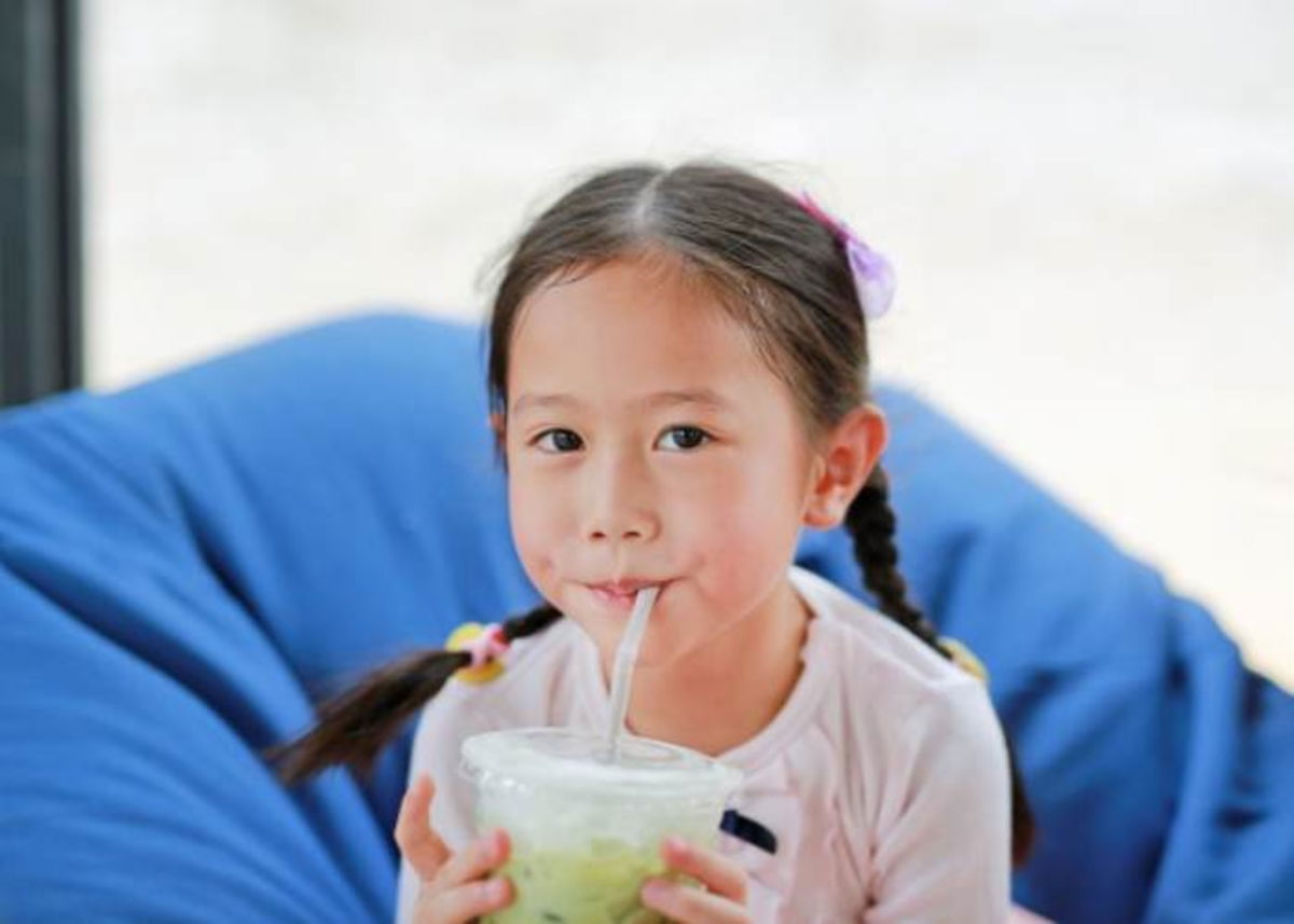 Niña tomando bebida verde