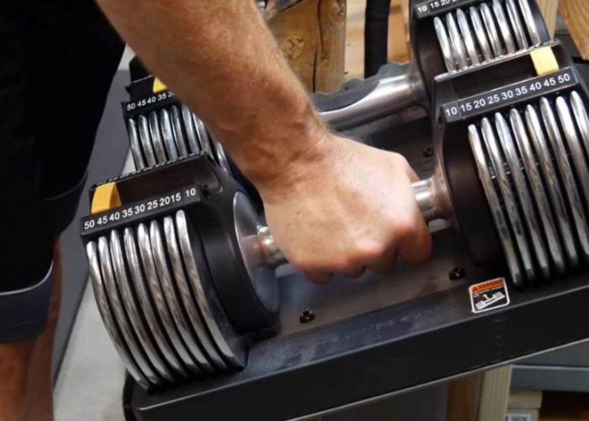 Persona tomando pesas ajustables