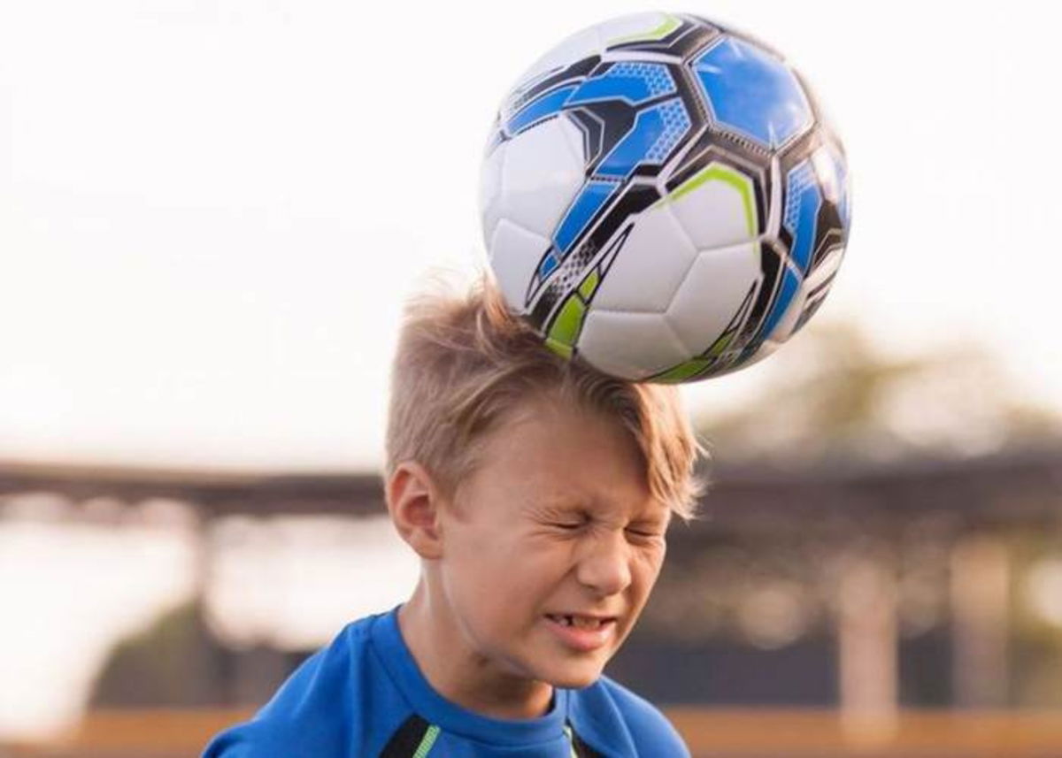 Niño pegándole a un balón con la cabeza